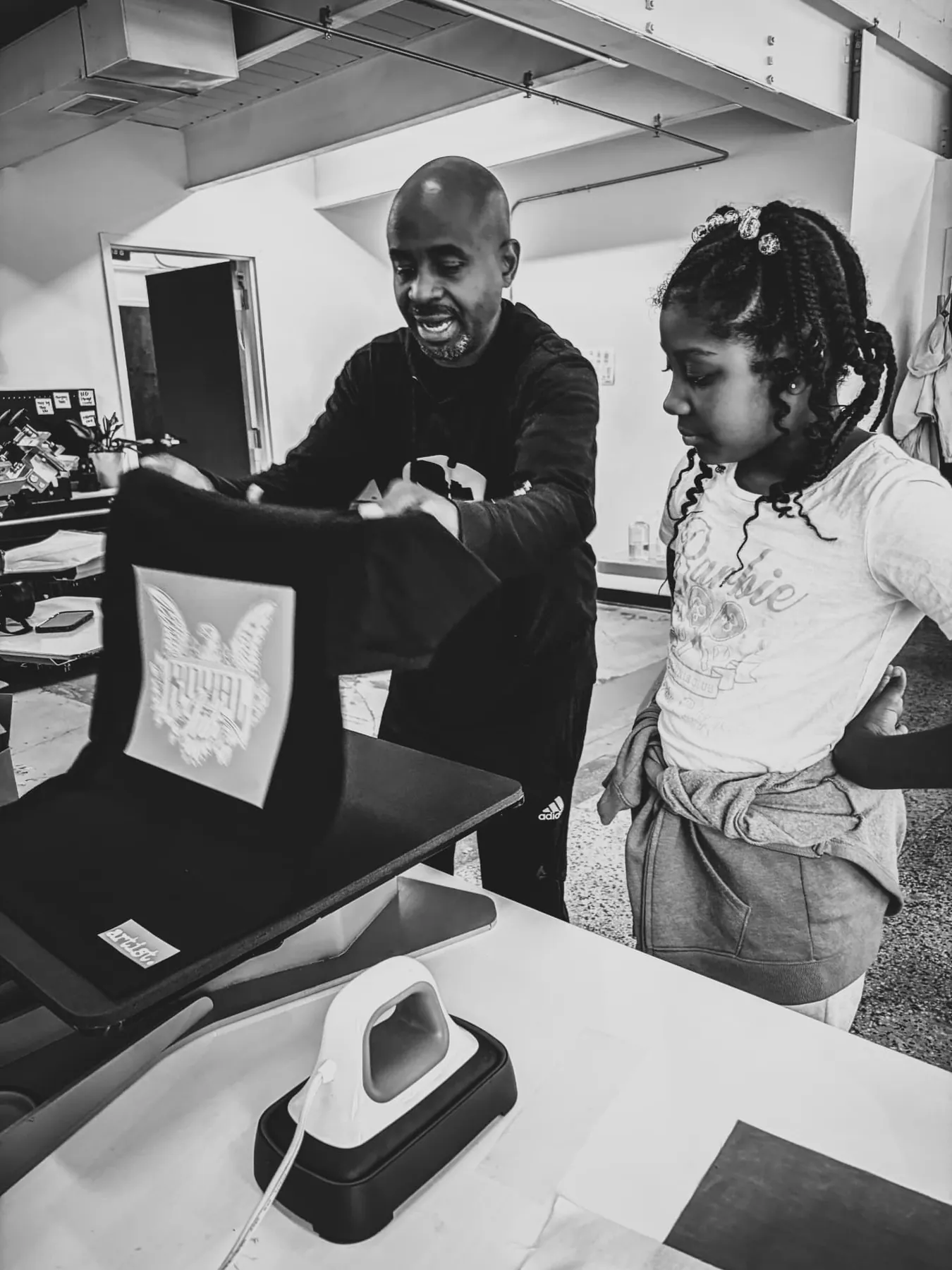 A mentor and a young printer operate the press together.
