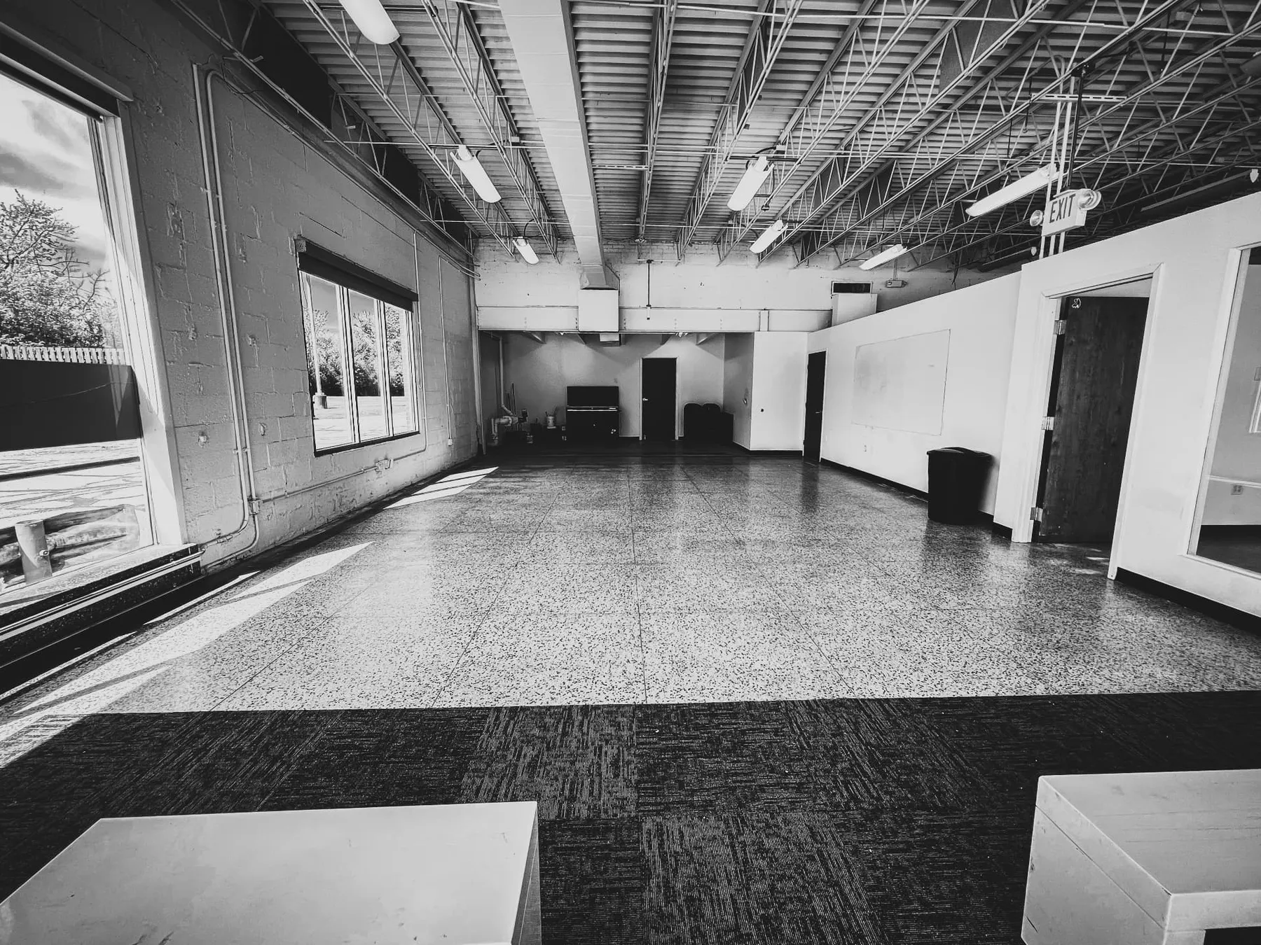 The empty Balance Point Studios space: a wide open room with speckled floors, tall windows and an open ceiling.